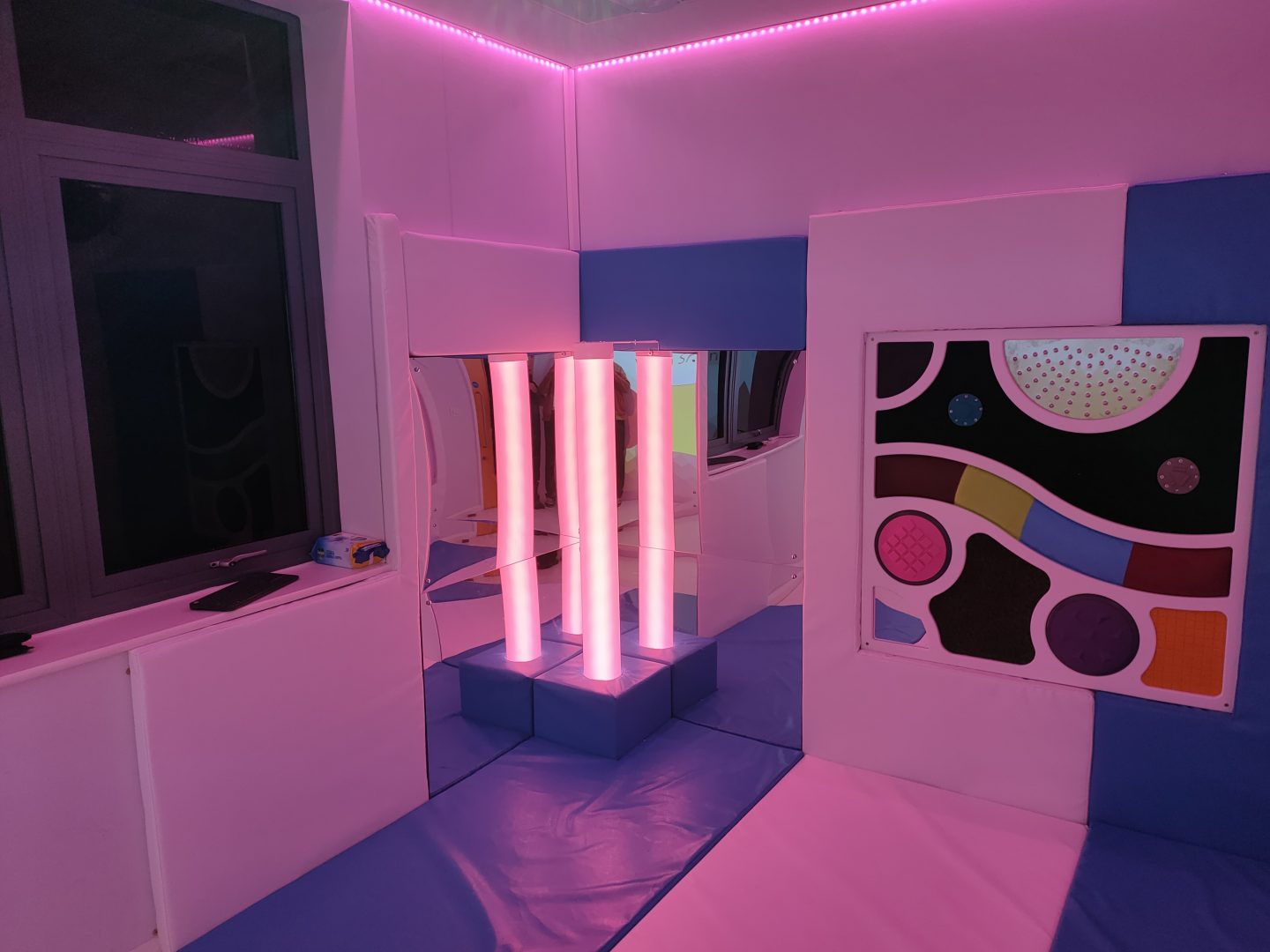 Well presented sensory corner, the walls and floor are soft padded in alternate blue and white with a soft padded plinth housing the calming waterless tube. There is also a tactile panel housed within the soft padding for the users of the sensory room to engage with.