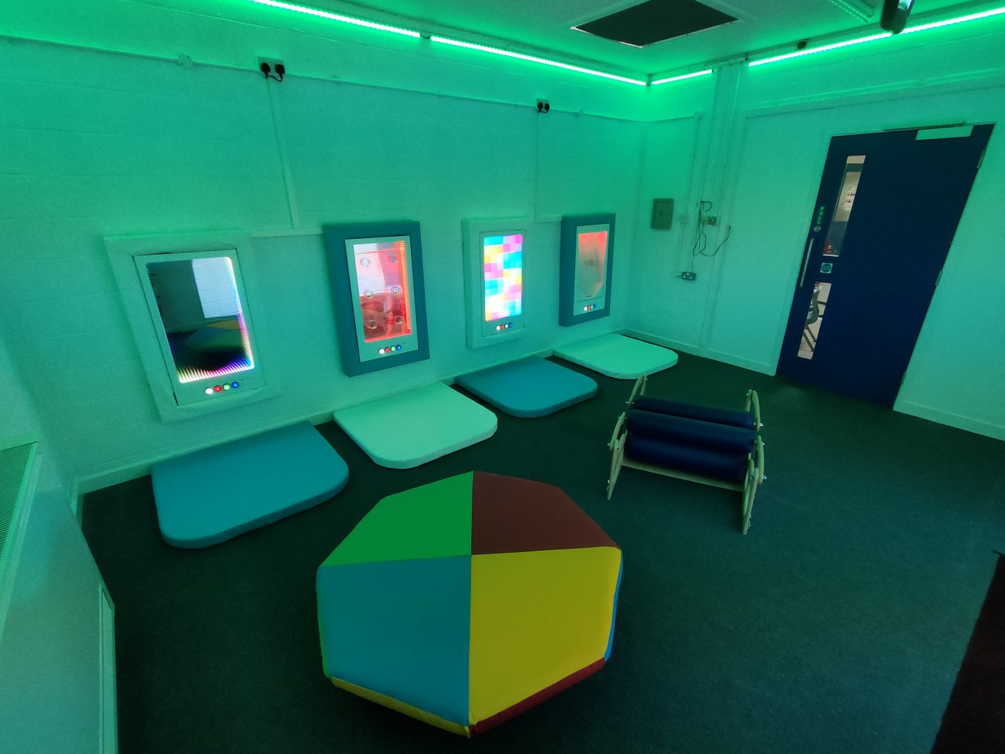 A well-equipped sensory room installed within a school environment, featuring interactive sensory panels such as the Snow-Scape interactive snow fall panel, The Infinity-Glow panel for infinite colourful reflections, The Spectra-Sync a multi mode interactive sound and light panel and a calming, colourful bubble wall. The Sensory room also features aspects of sensory integration with the soft padded rocker roller and the sensory body roller. Mood lighting around the Sensory Room is controlled by a soft padded cube.