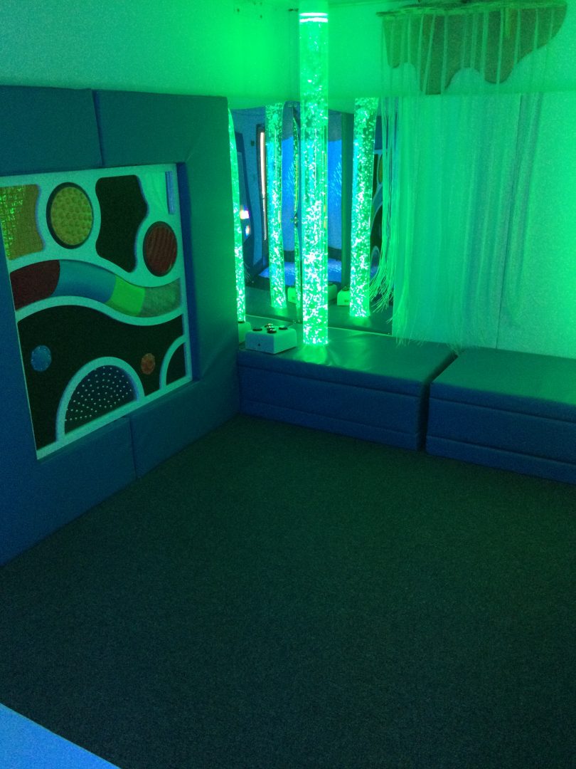 Bubble tube installed into a sensory room along side fibre optics and a tactile sensory wall panel
