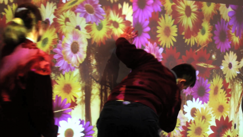 Two children scattering colourful flowers on an the interactive wall
